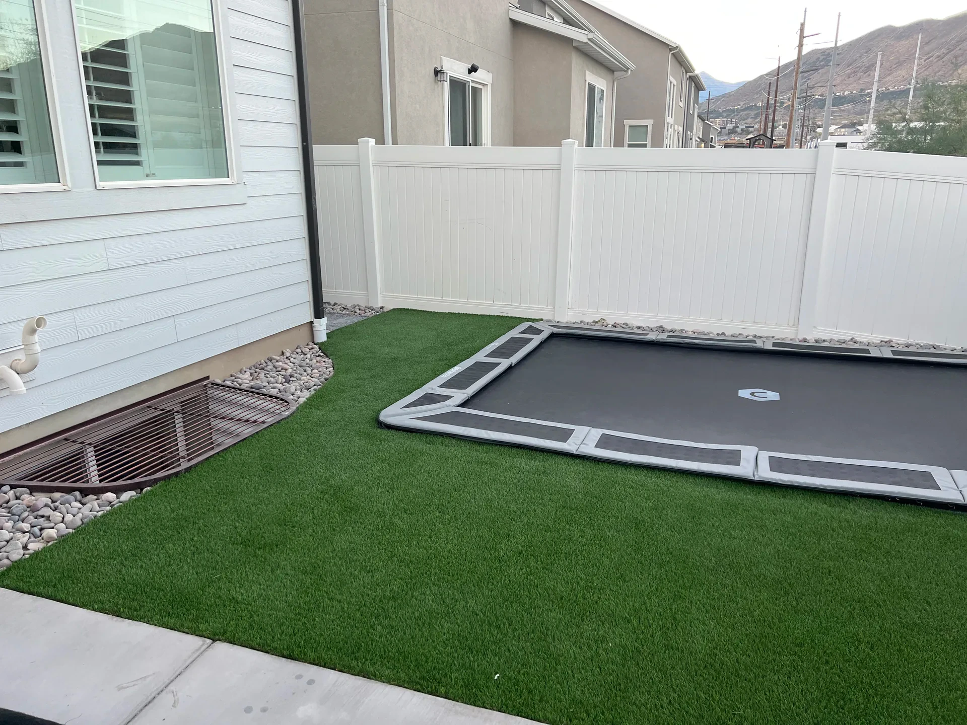In-ground trampoline surrounded by artificial turf and decorative rock in Bluffdale, Utah.