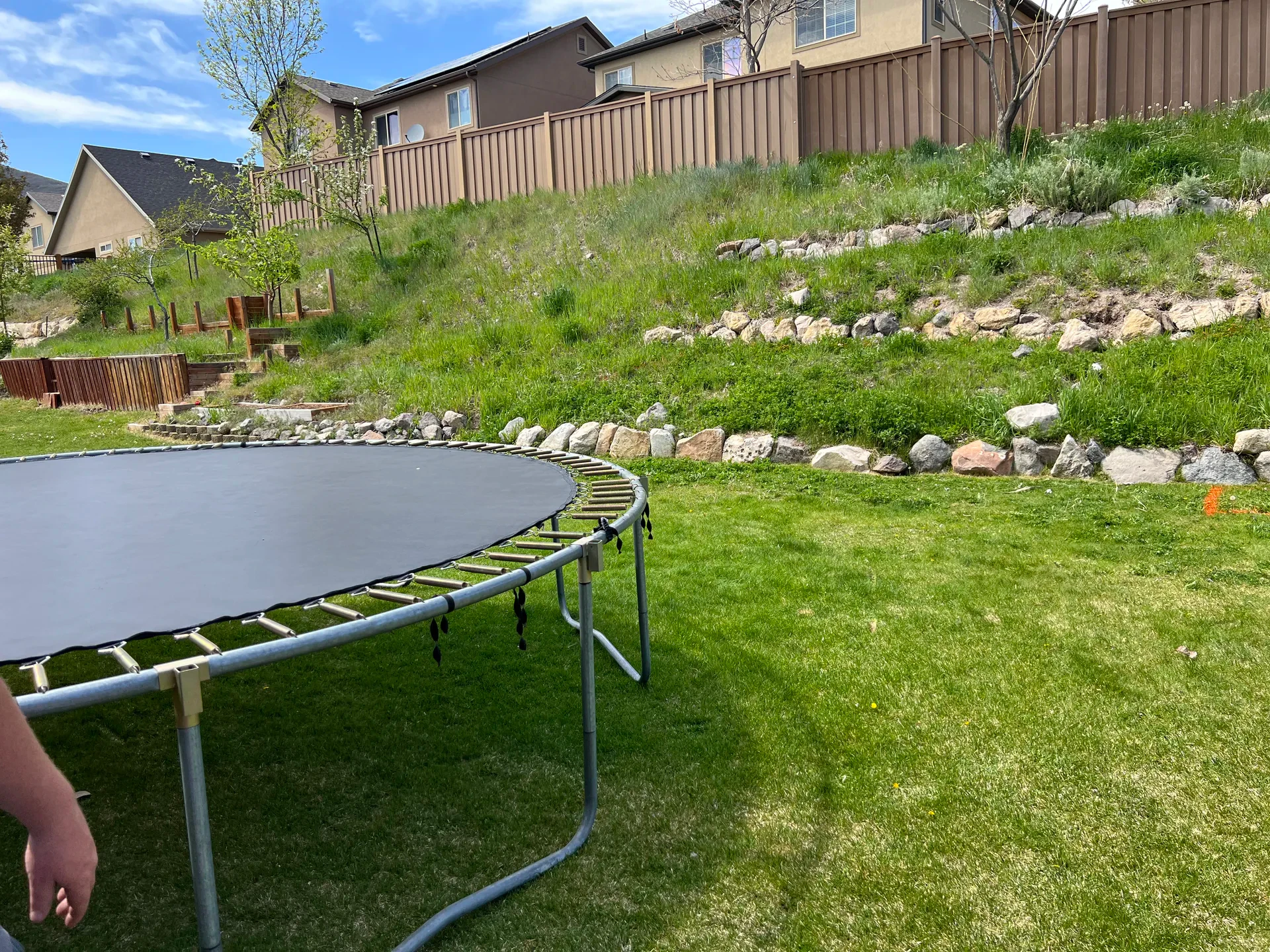 Draper backyard before renovation — unimproved slope with trampoline
