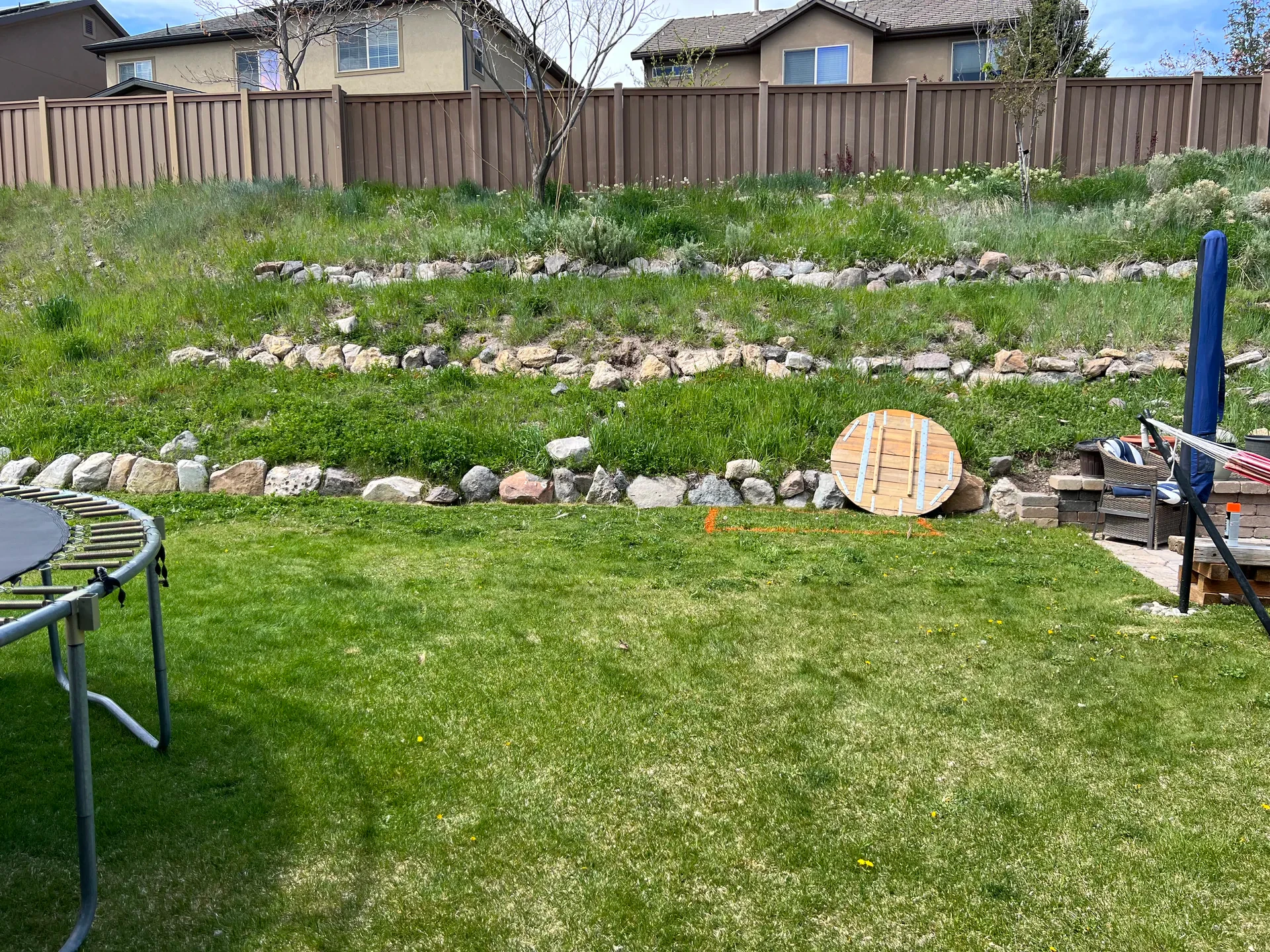 Draper backyard before renovation — rocky slope and trampoline