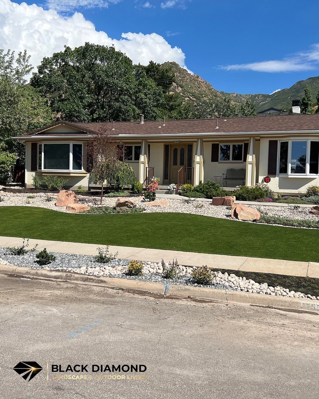 Emigration Canyon front yard after renovation — artificial turf, rock border, and mountain backdrop