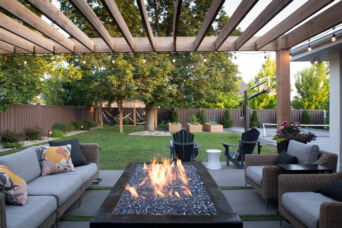 Rectangular custom fire feature set within a concrete patio beneath a Millcreek backyard pergola