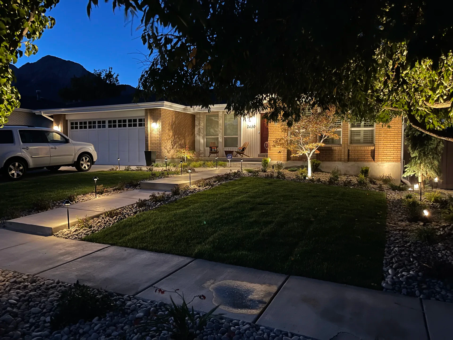 Millcreek front entry with BioGrass lawn, concrete walk, planting beds and landscape lighting at blue hour