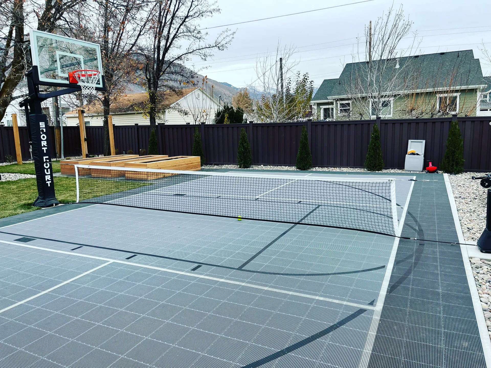 Custom Millcreek sport court beside raised garden boxes and a finished landscape recreation area