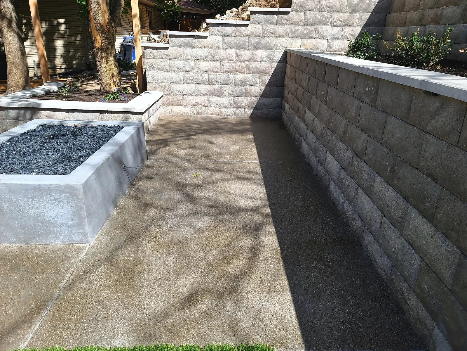 Belgard Diamond Pro Ashwood retaining wall with Melville Scandina caps beside a concrete fire feature and patio