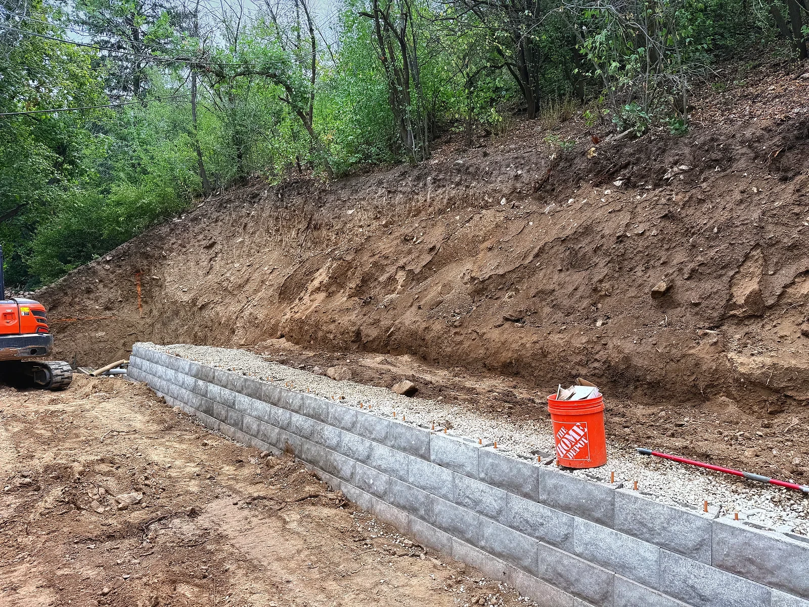 First tier of Belgard block retaining wall with gravel backfill during construction