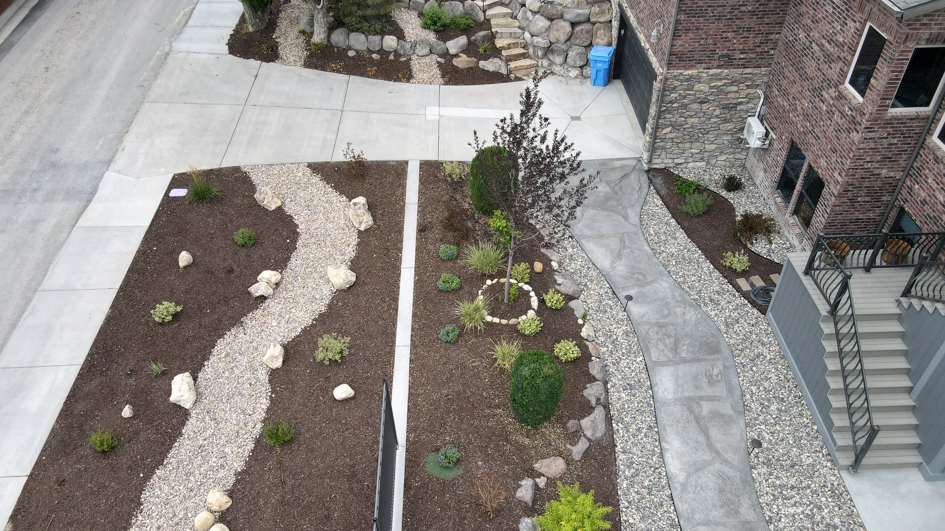 Aerial view of completed Riverton backyard showing planting beds, rock channels, and pathways