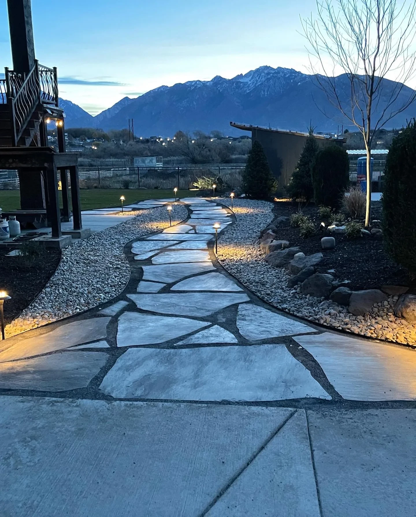 Flagstone pathway with low-voltage path lights and mountain backdrop at dusk