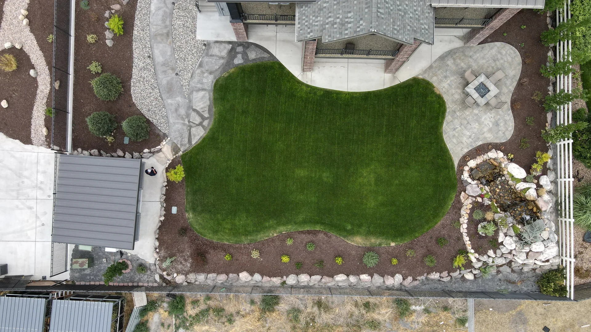 Aerial overview of completed Riverton backyard with patio, fire feature, and water feature