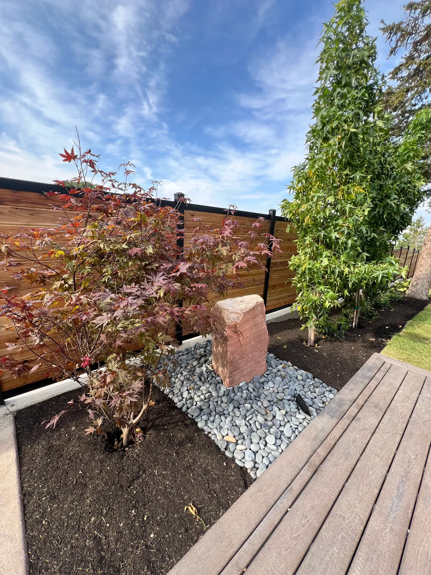 Drilled-rock water feature in a decorative river-cobble basin with new planting in Sandy, Utah