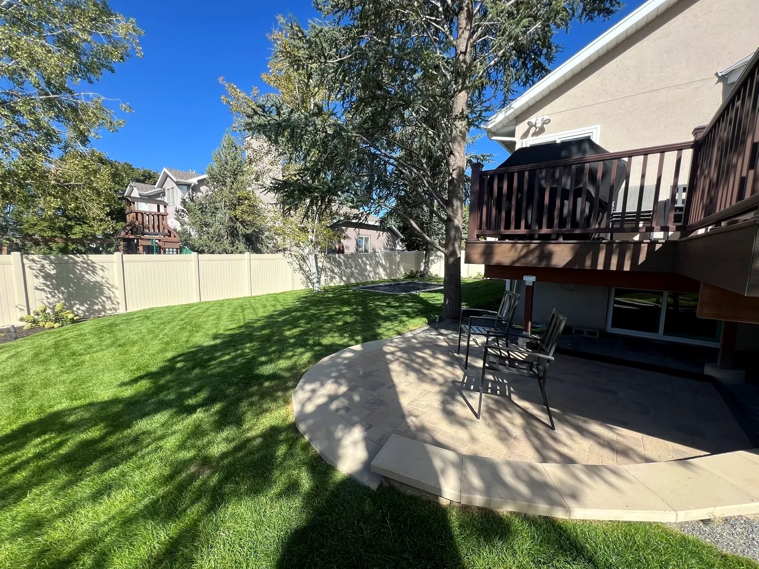 Circular Belgard patio and lawn beside a raised deck in Sandy