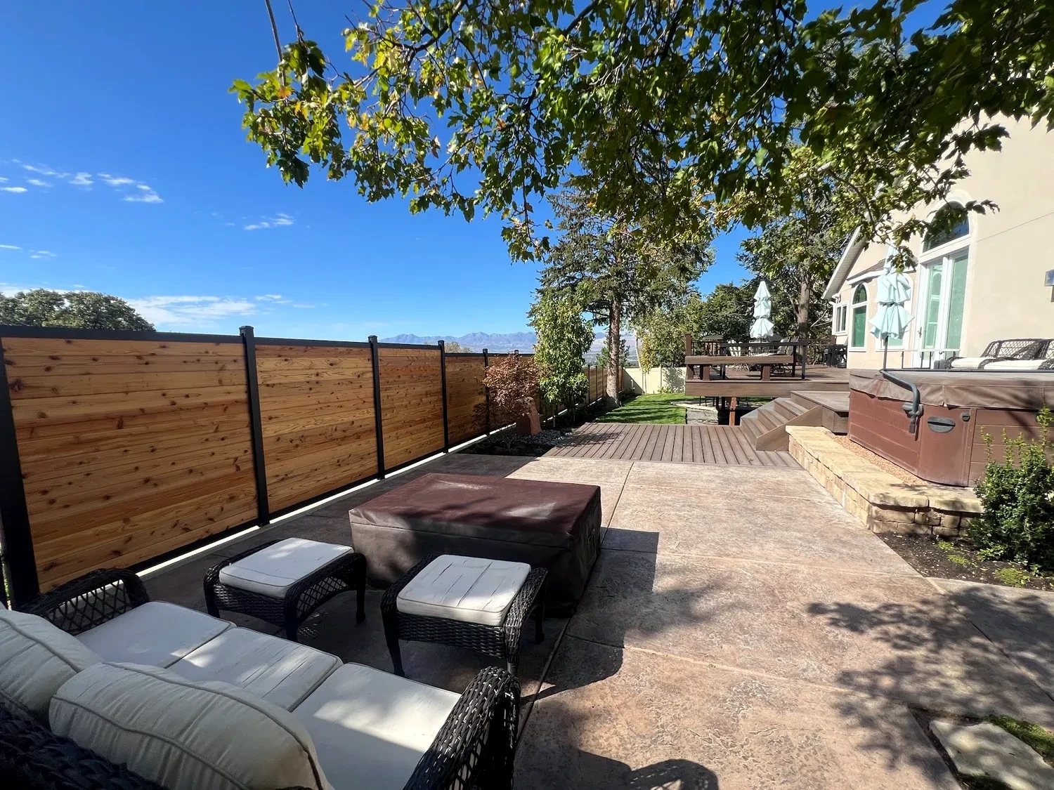 Outdoor living patio with hot tub, fire table, and cedar privacy fence in Sandy, Utah
