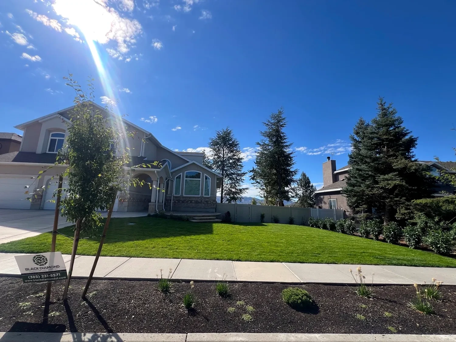 Street view of a finished Sandy front yard with a Black Diamond Landscape yard sign