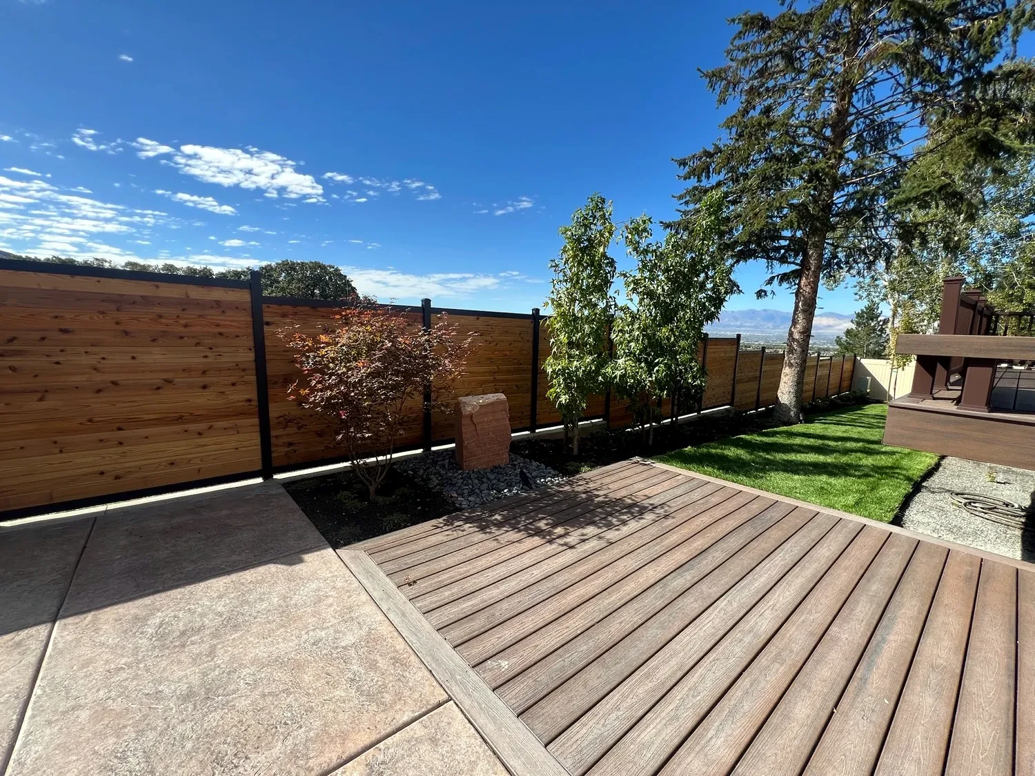 Drilled sandstone water feature, river cobble, cedar fence, and deck boards in Sandy
