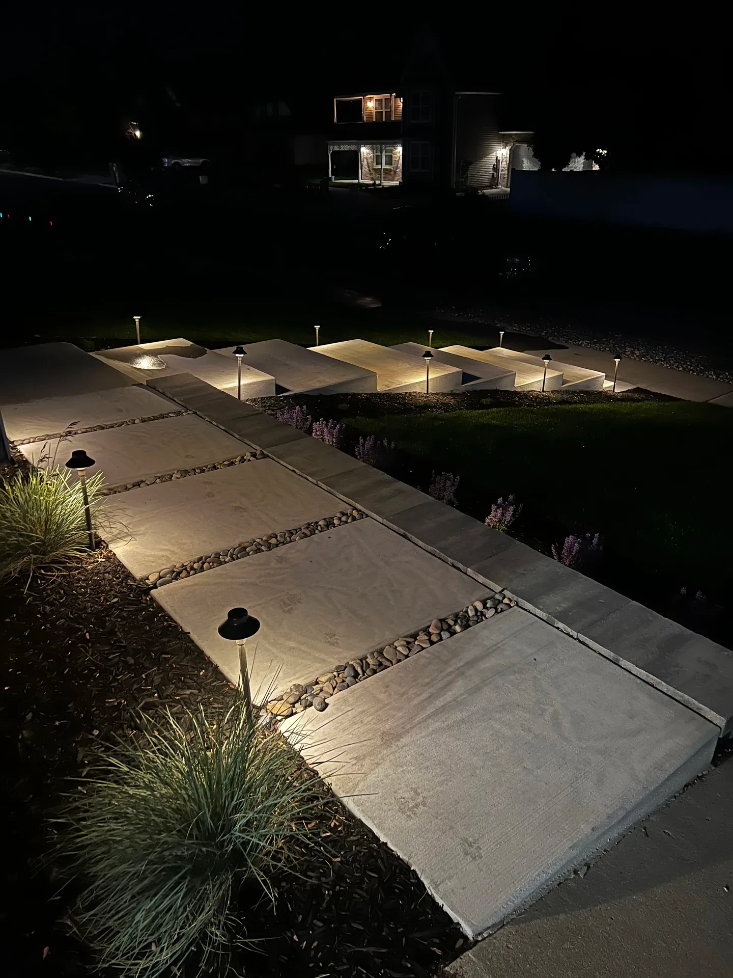 Illuminated custom concrete front entry at evening, Sandy Utah landscape renovation