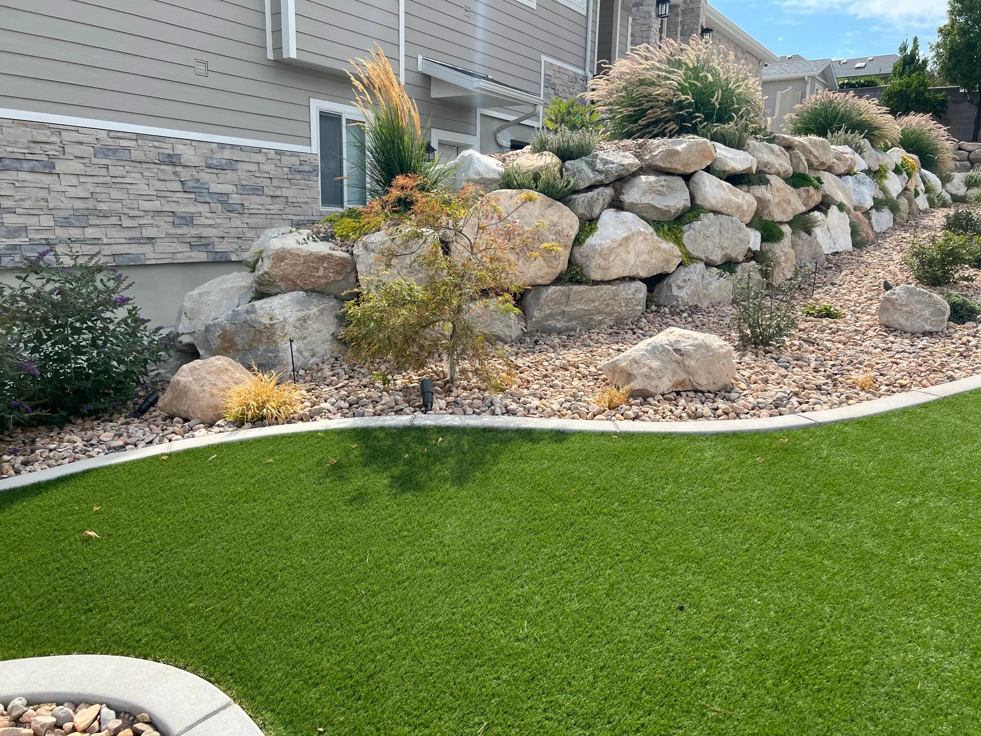 Artificial turf, decorative stone and natural boulder wall in South Jordan, Utah.