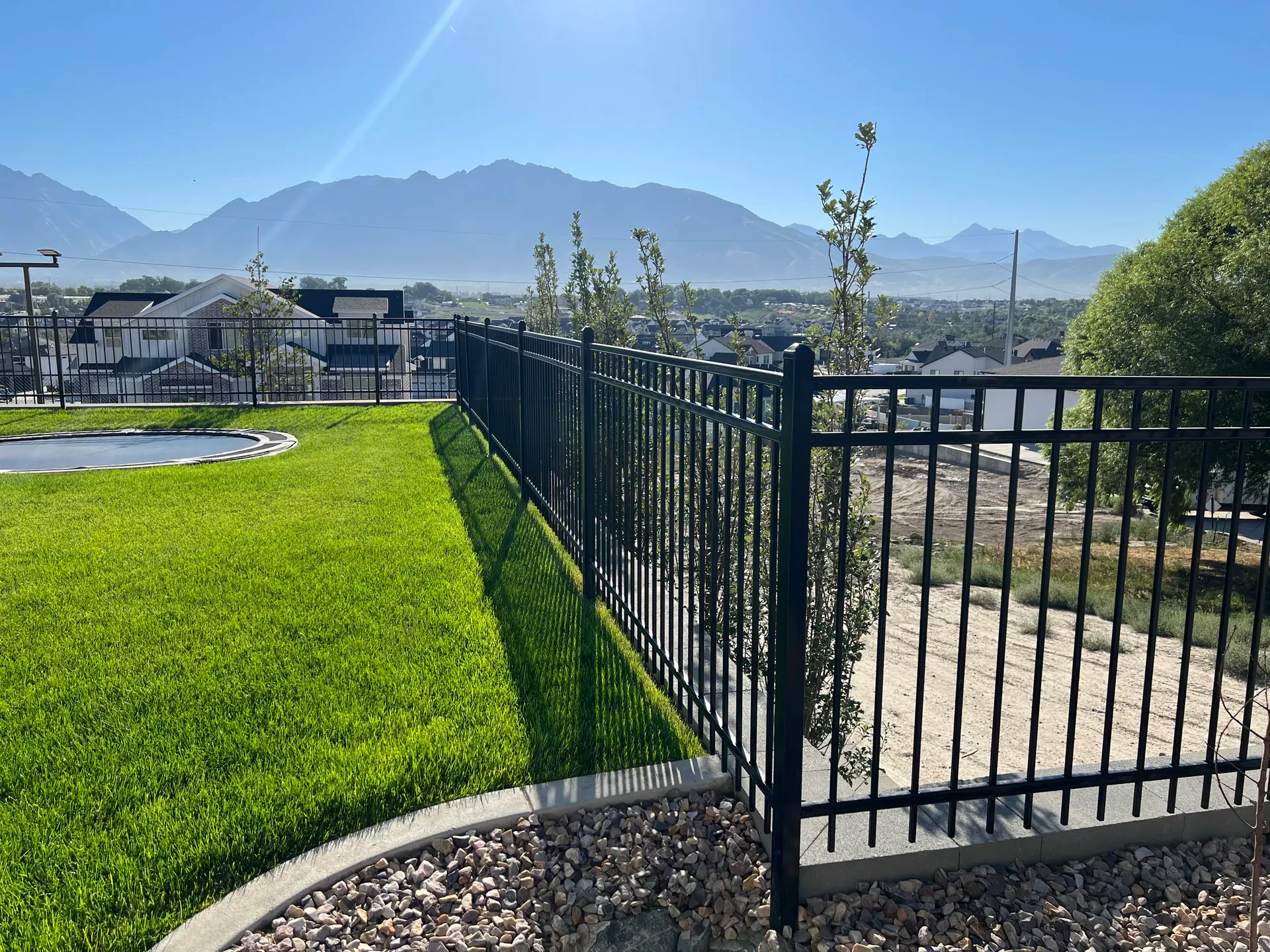Artificial turf beside a fenced sport court with mountain views in South Jordan, Utah.