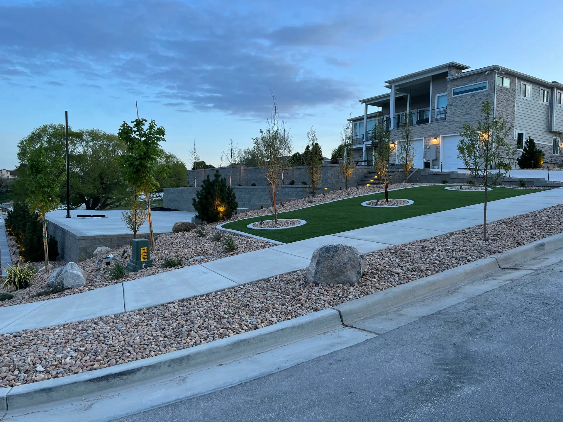 Complete South Jordan front landscape with retaining walls, decorative stone and lighting at blue hour.