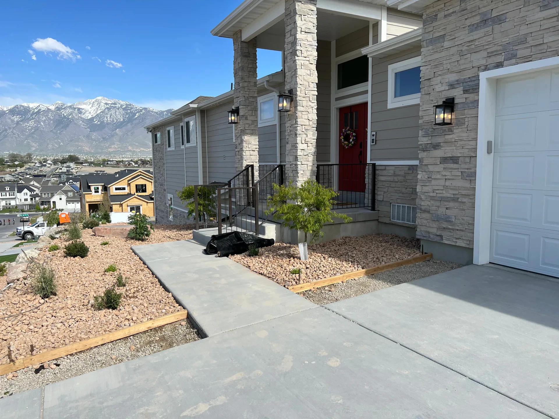 Custom concrete front entry with decorative stone and planted landscape beds in South Jordan, Utah.