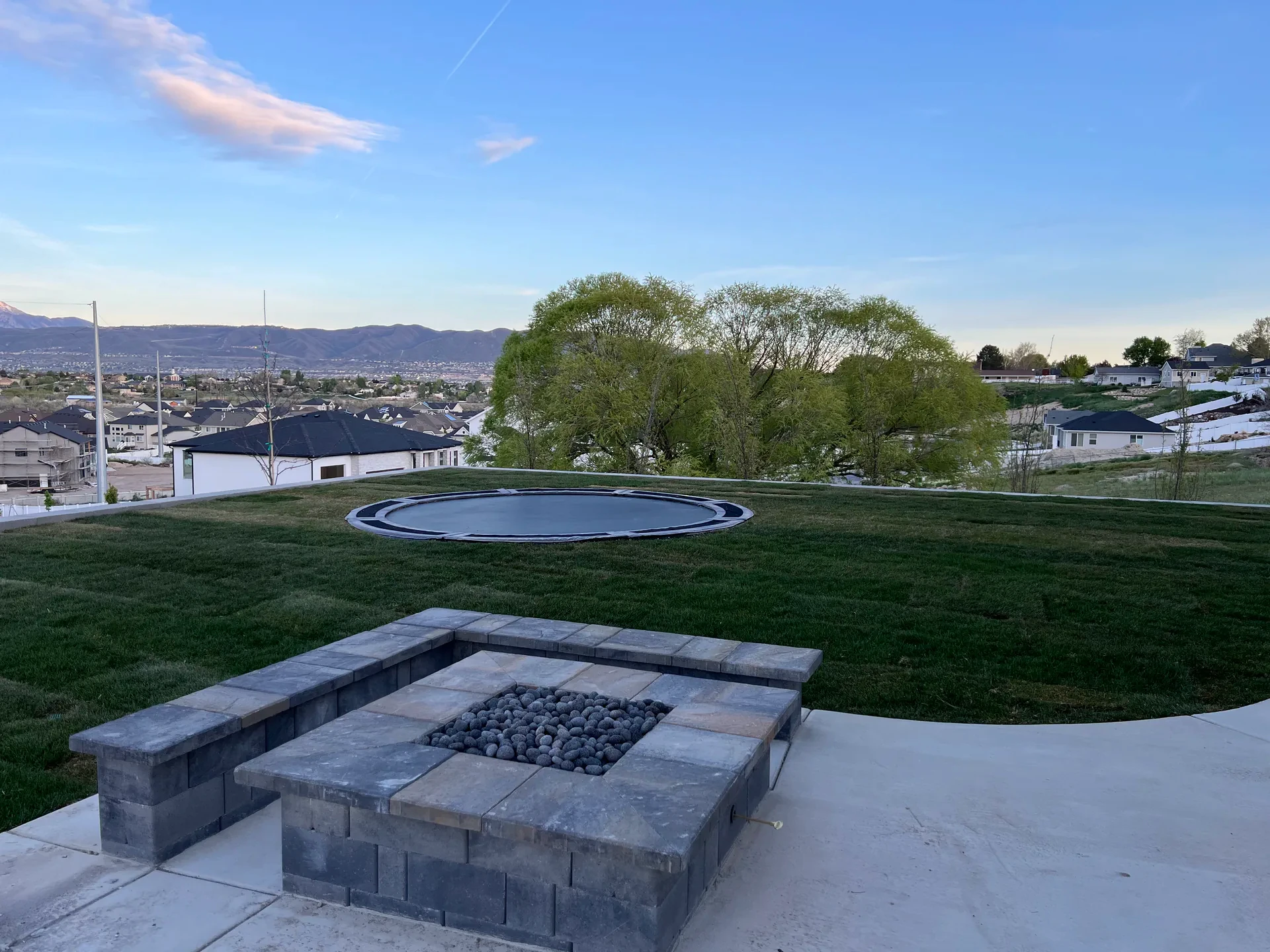 Custom fire feature beside artificial turf with mountain views in South Jordan, Utah.