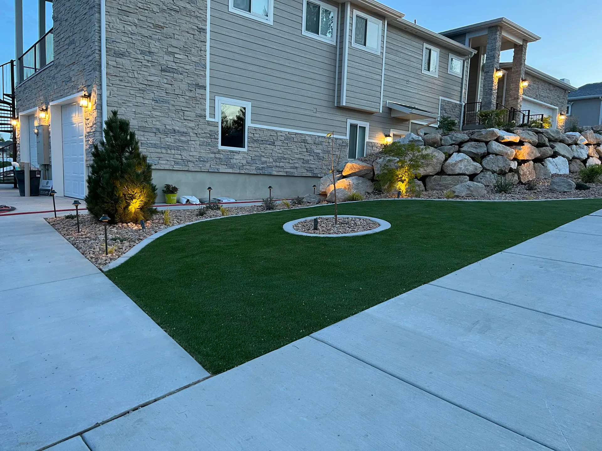Artificial turf, natural boulder wall and low-voltage landscape lighting at blue hour in South Jordan, Utah.