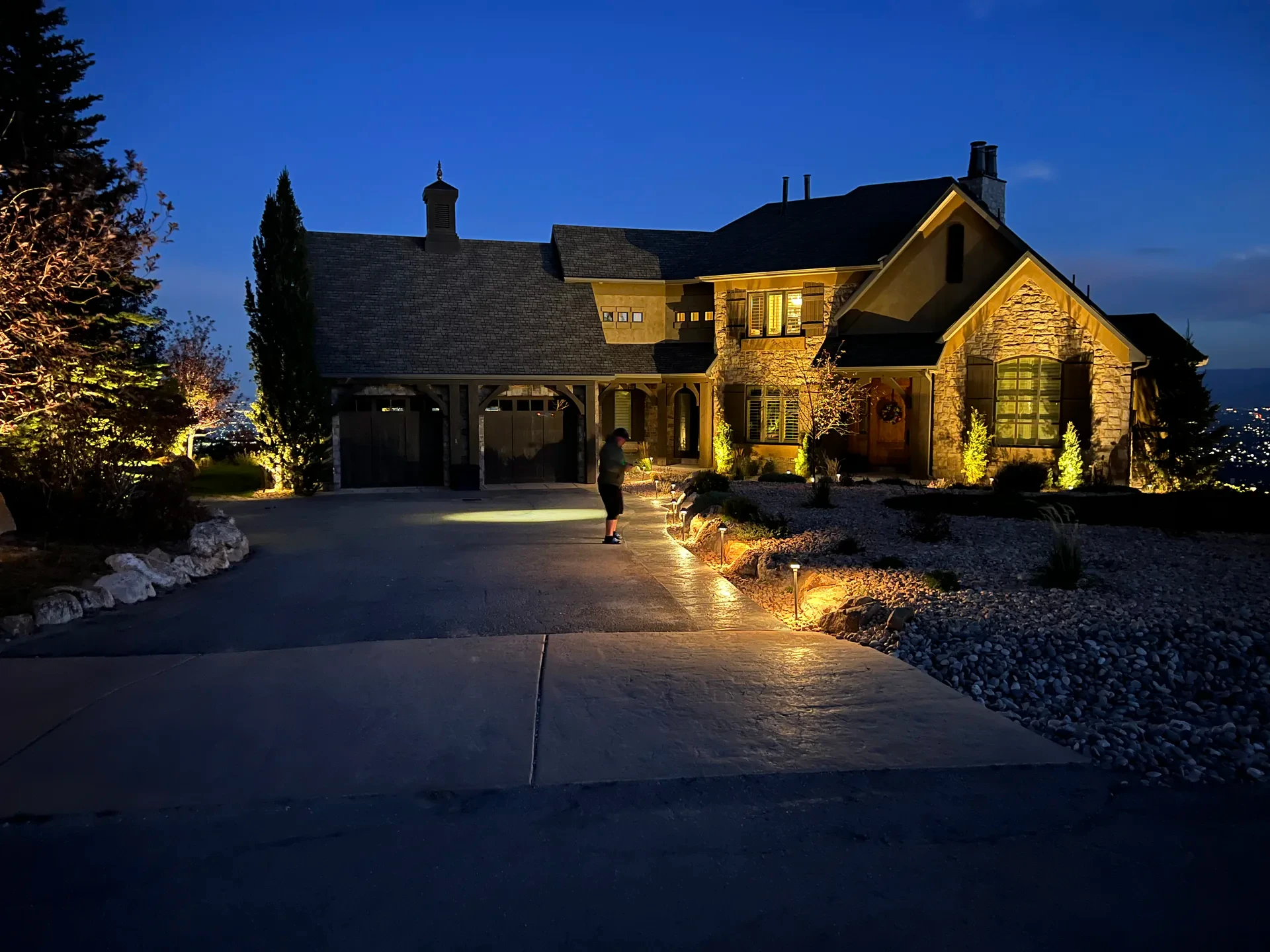 Illuminated front entry of a Suncrest home with water-wise landscape at dusk