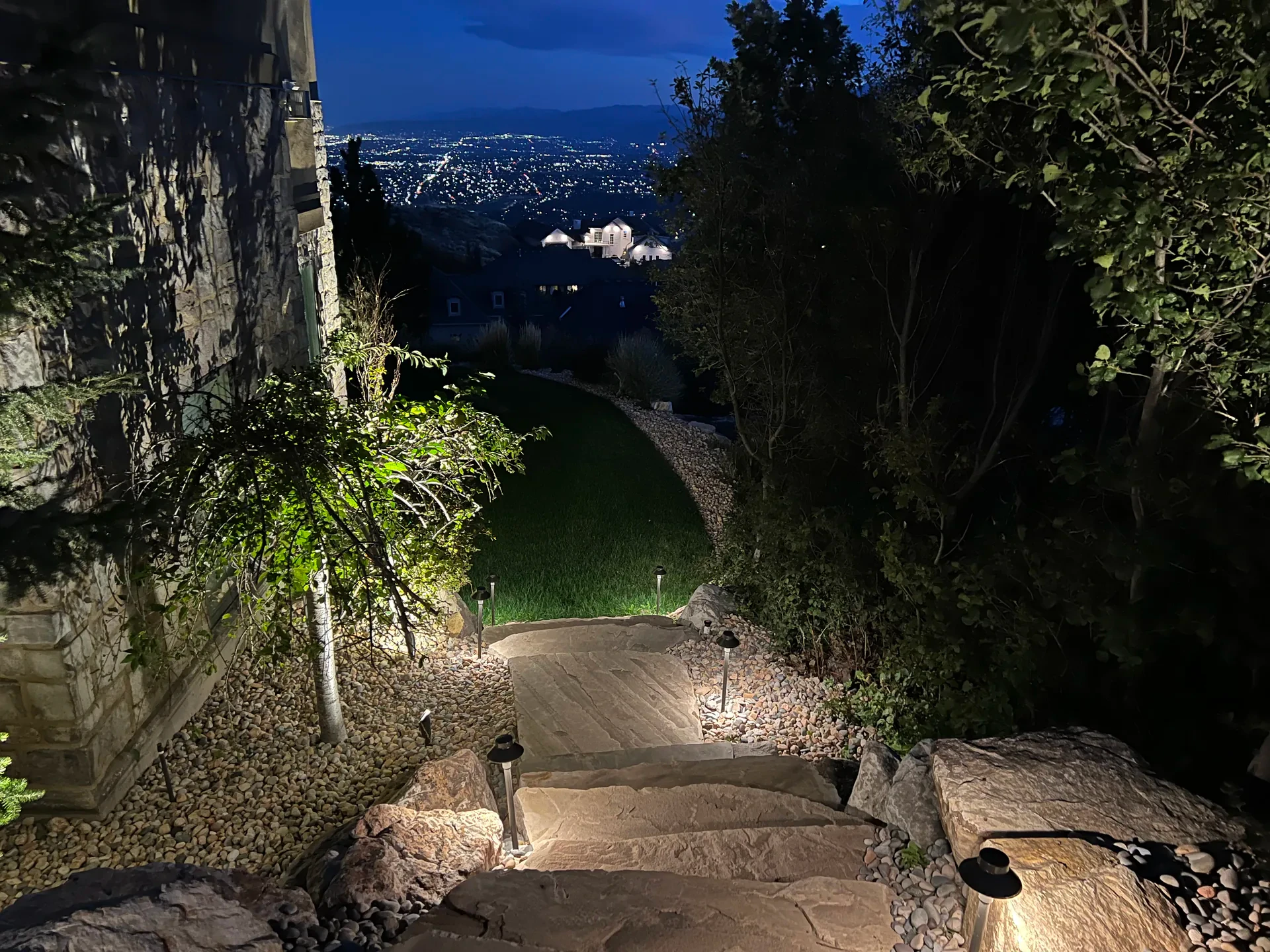 Illuminated natural stone steps at night with city lights visible below, Suncrest
