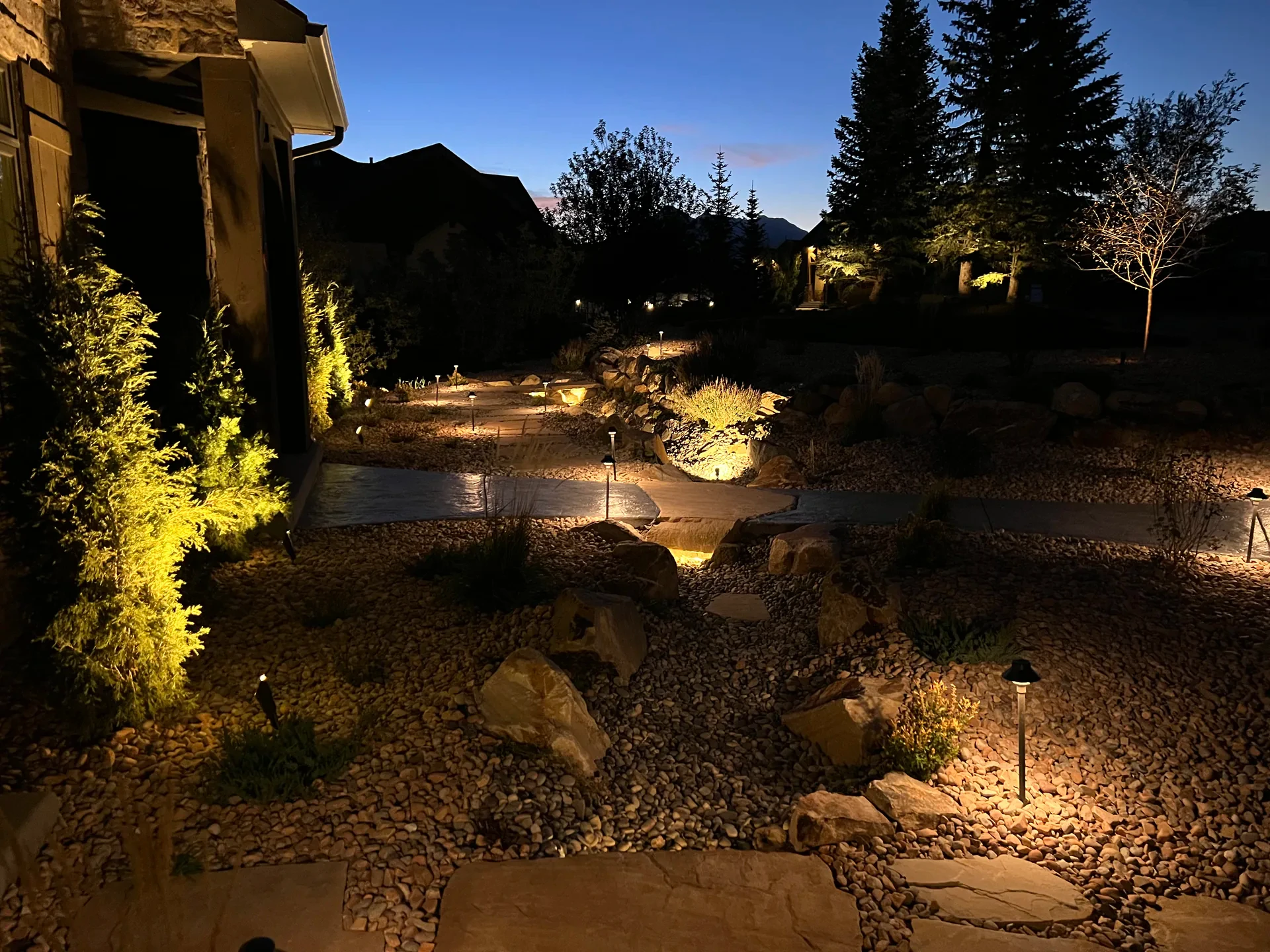 Illuminated natural slab pathway with landscape lighting and mountain views at night