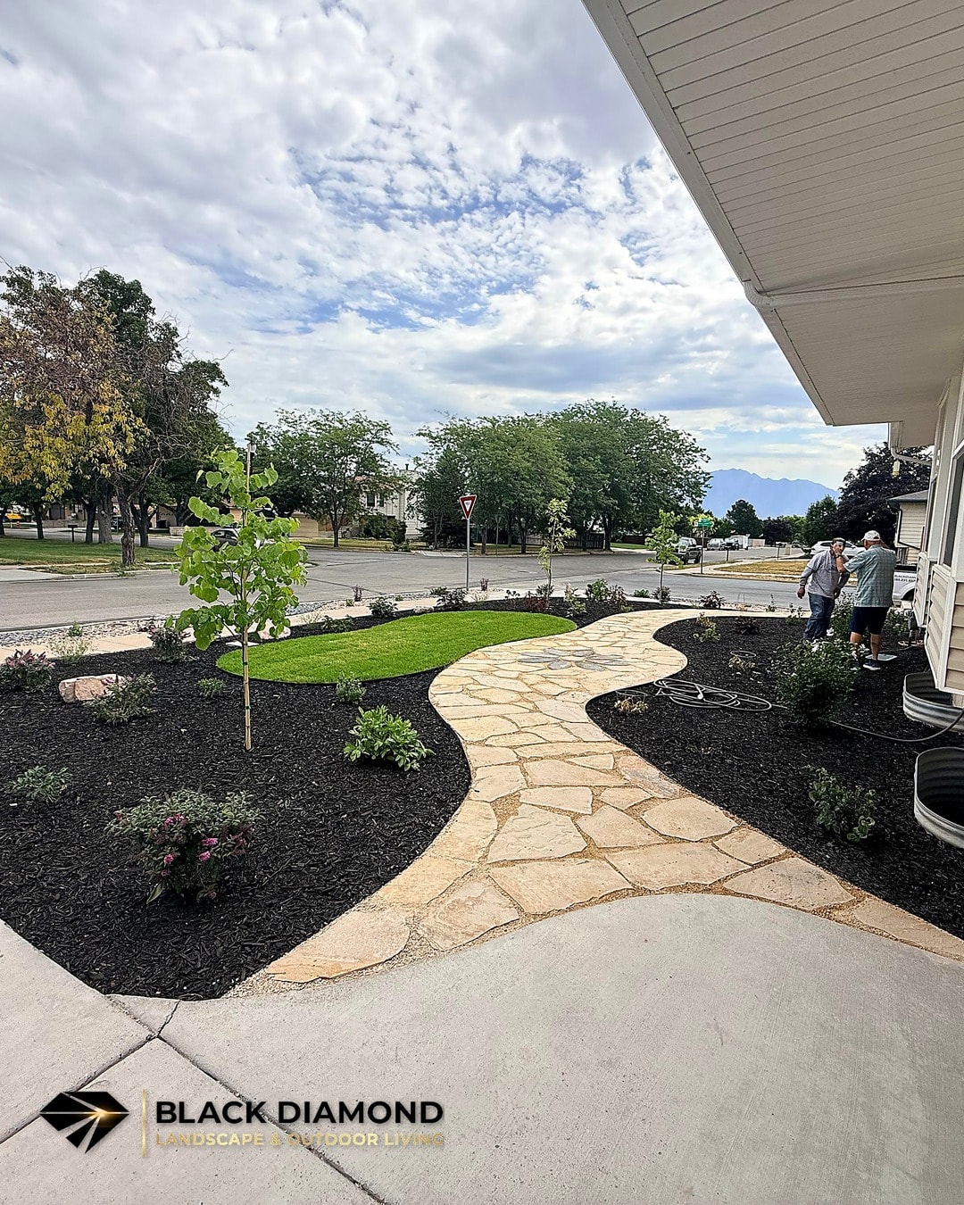 West Jordan front yard after renovation — flagstone walkway, planting beds, and water-wise rock strip replacing traditional lawn