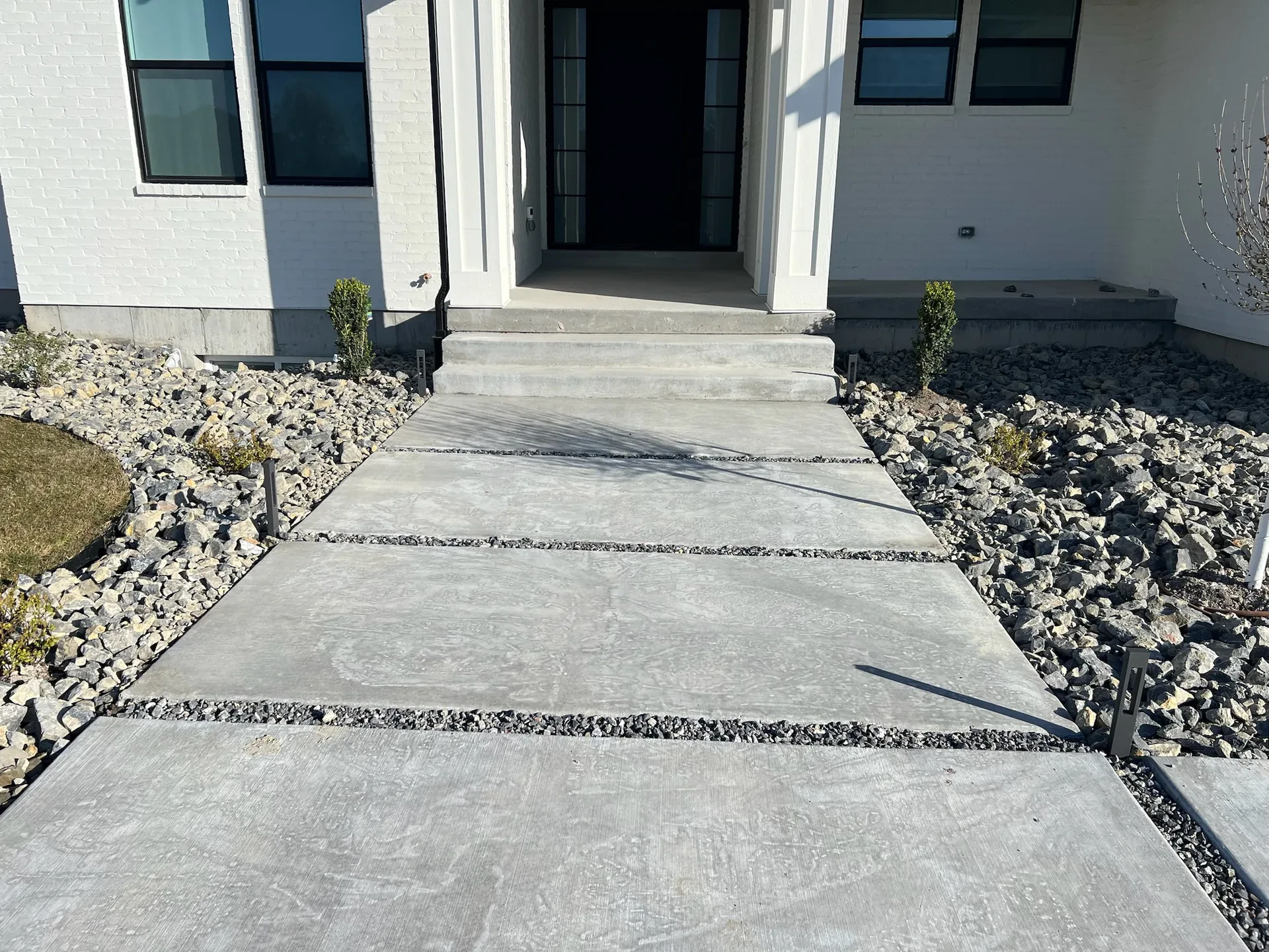 Concrete entry steps and walk panels with decorative-rock joints in a West Valley City landscape