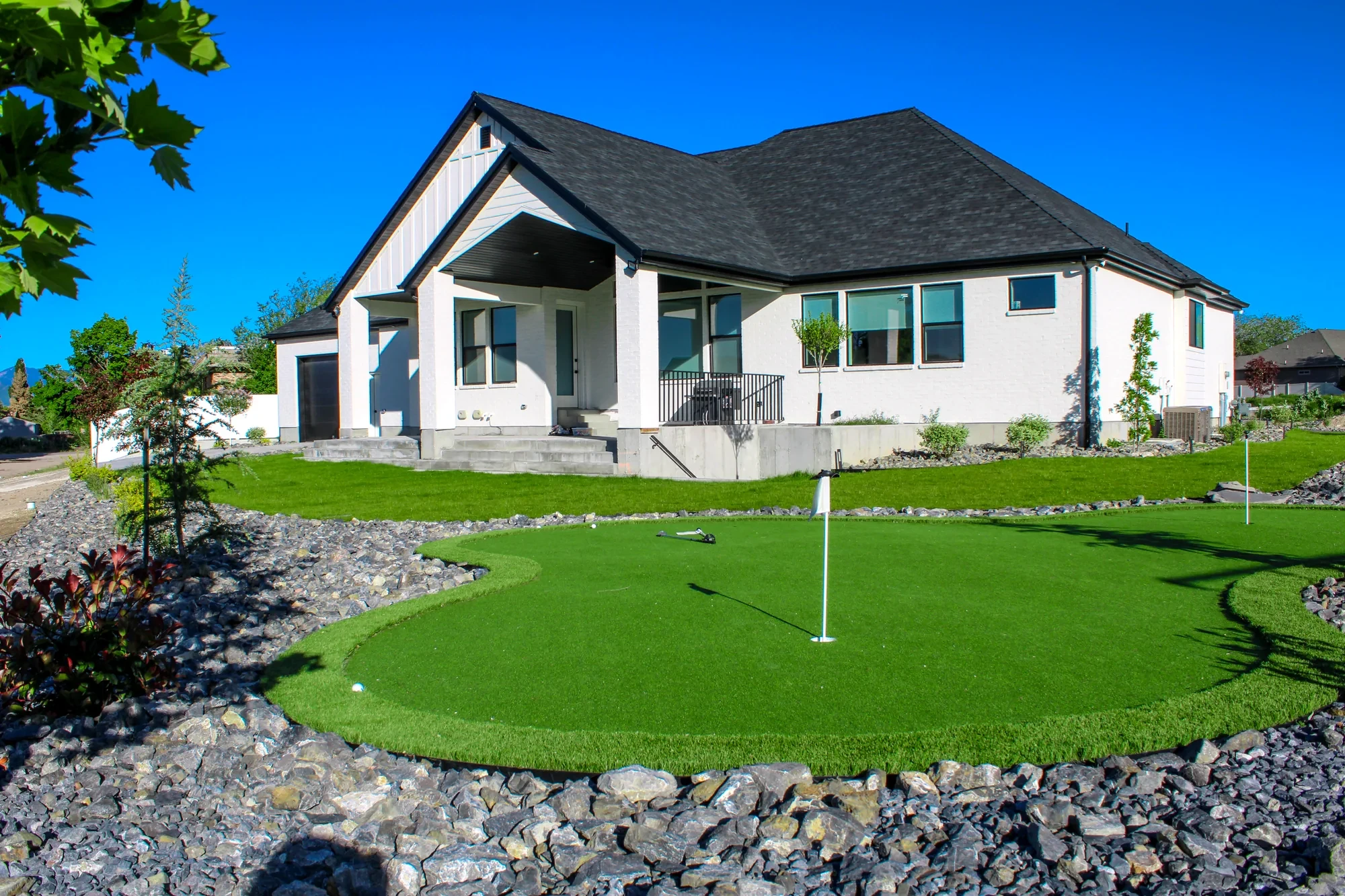 Custom putting green with decorative rock border, lawn and planting in West Valley City