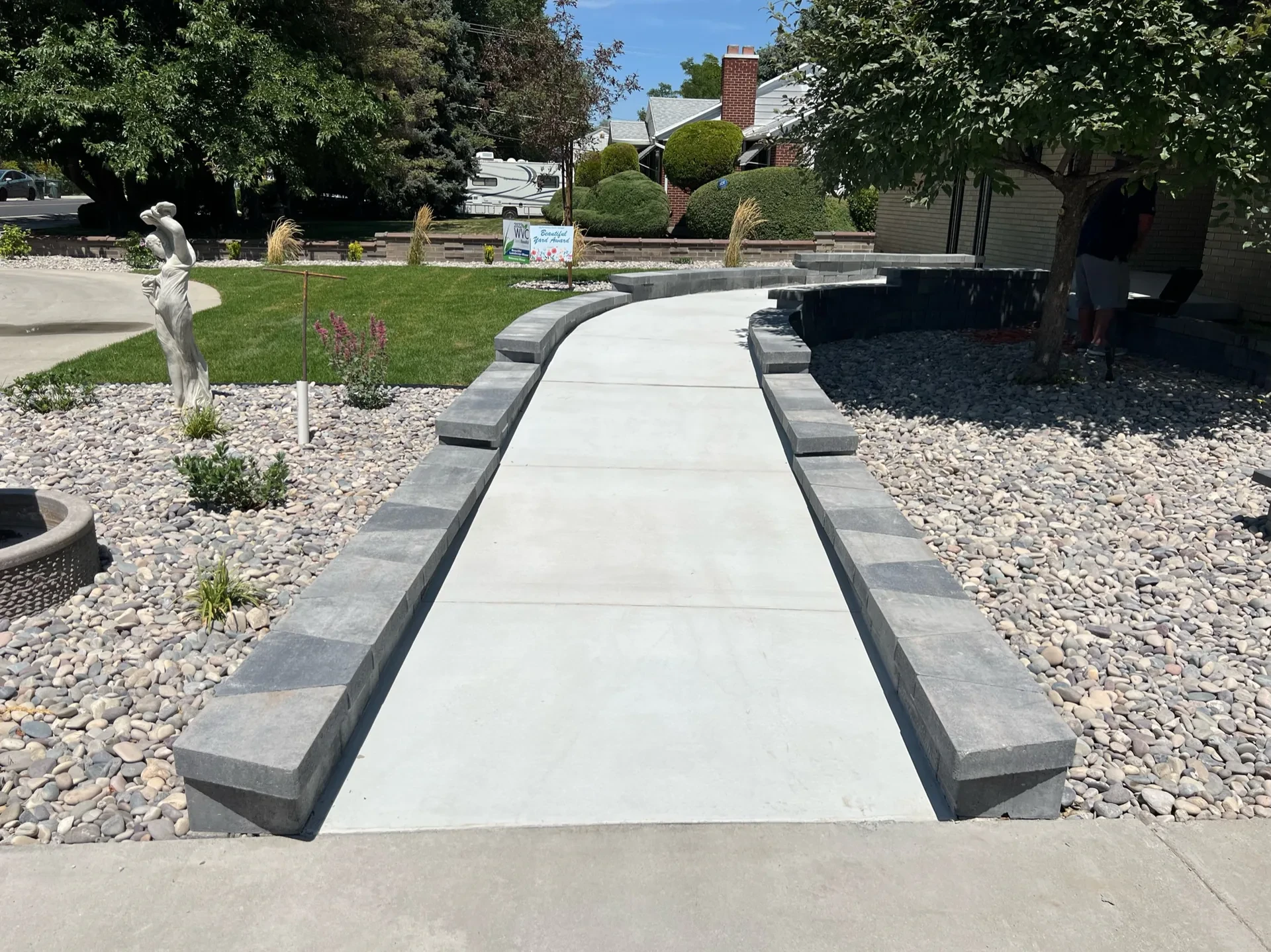 Curving accessible concrete ramp bordered by decorative stone and drought-tolerant planting in West Valley City