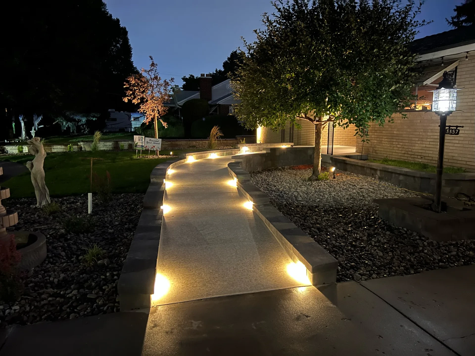 Low-voltage step lights illuminate a curving accessible concrete ramp in a West Valley City landscape at dusk