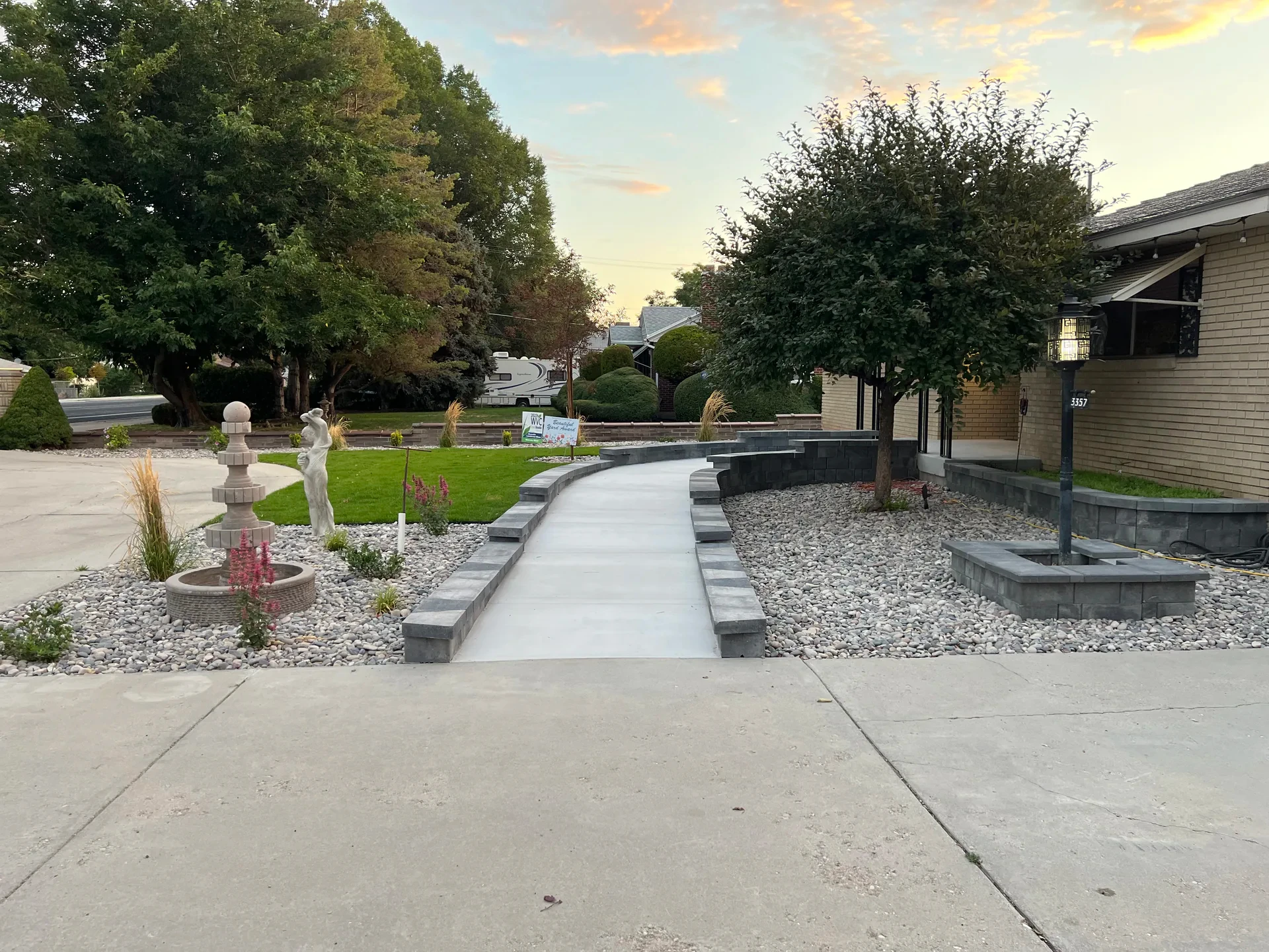 Curving concrete accessibility ramp with low retaining wall, decorative stone and planting in West Valley City