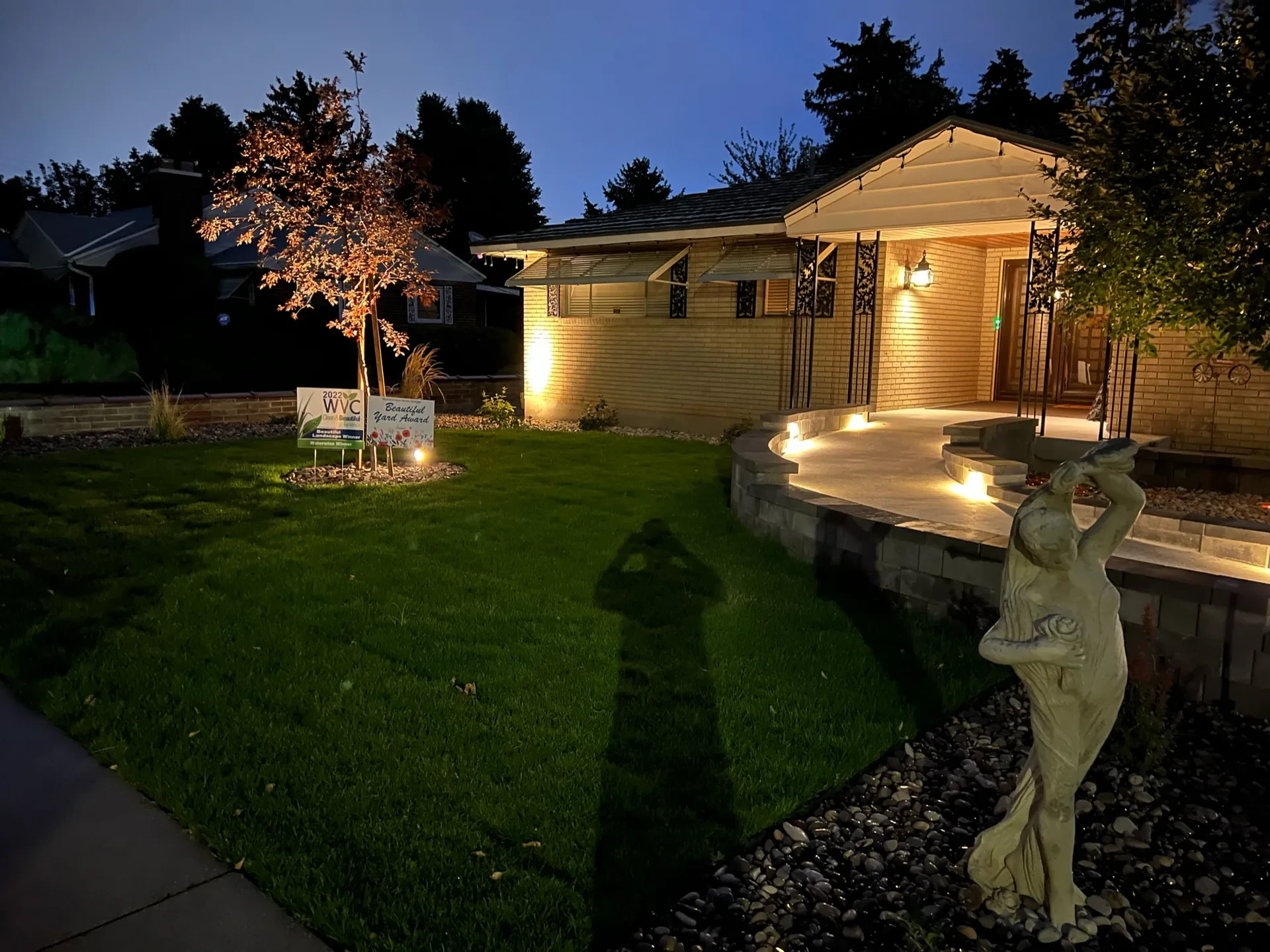 Illuminated front landscape water feature with planting and low-voltage lighting at a West Valley City home