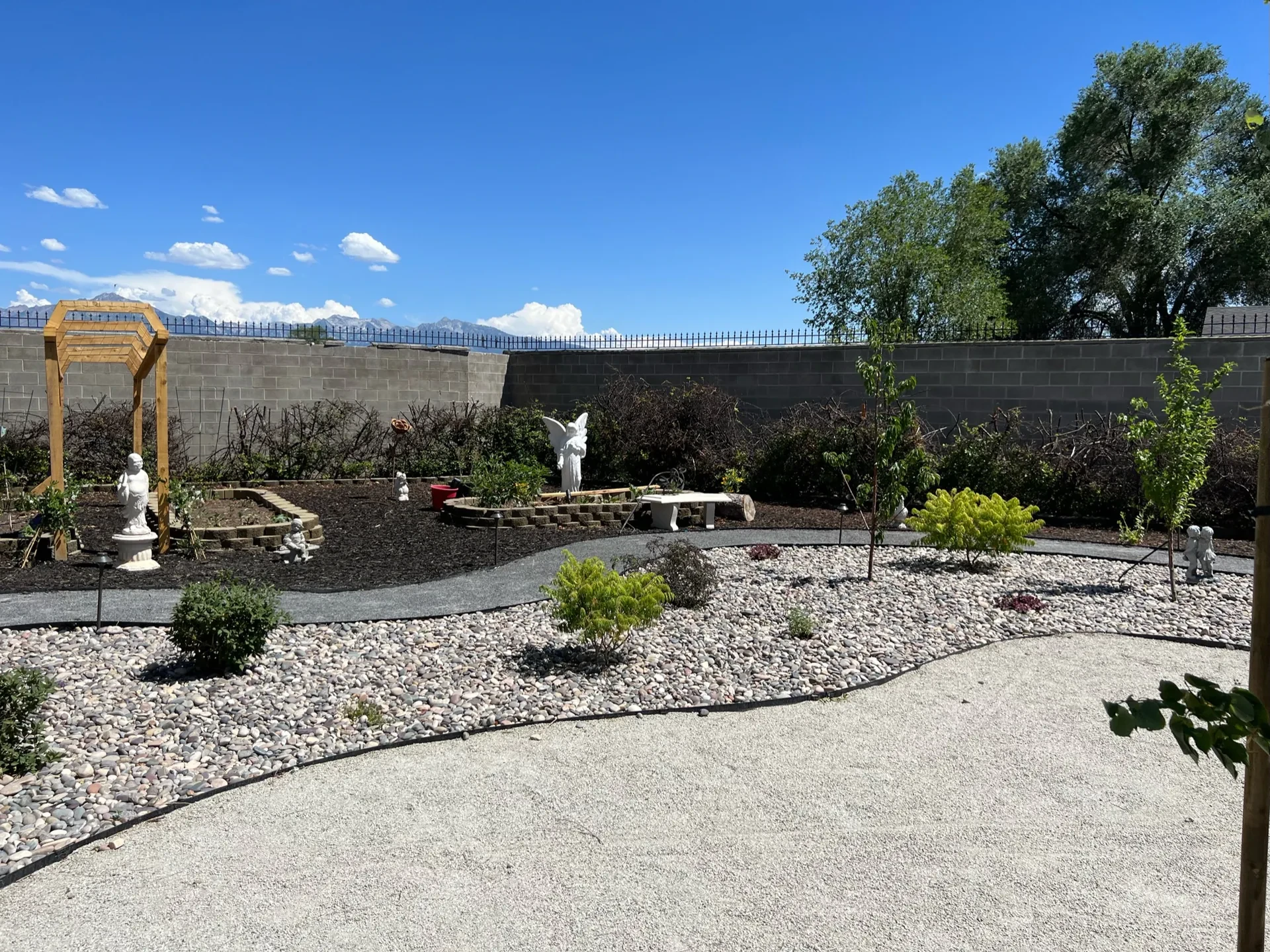 West Valley City backyard landscape with decorative stone, drought-tolerant planting, pergola and durable circulation paths