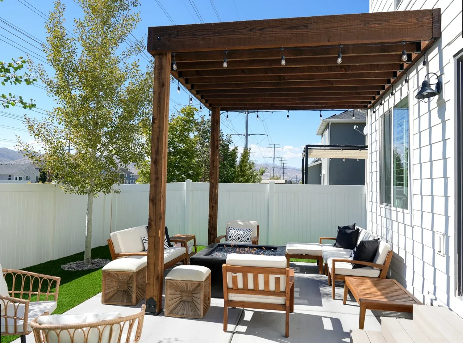 Attached wood pergola over a patio fire table and lounge seating