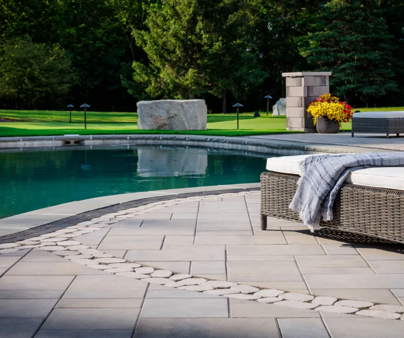 Belgard Dimensions 18 paver patio with Brooklyn Paver border, Belgian Cobble inlay, and Melville Tandem Wall columns — manufacturer inspiration.