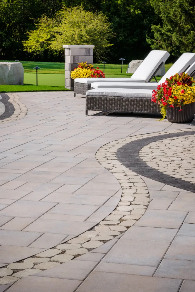 Belgard Dimensions 18 Moonlight patio with Belgian Cobble inlay, Brooklyn Paver border, and Melville Tandem Wall columns — manufacturer inspiration.