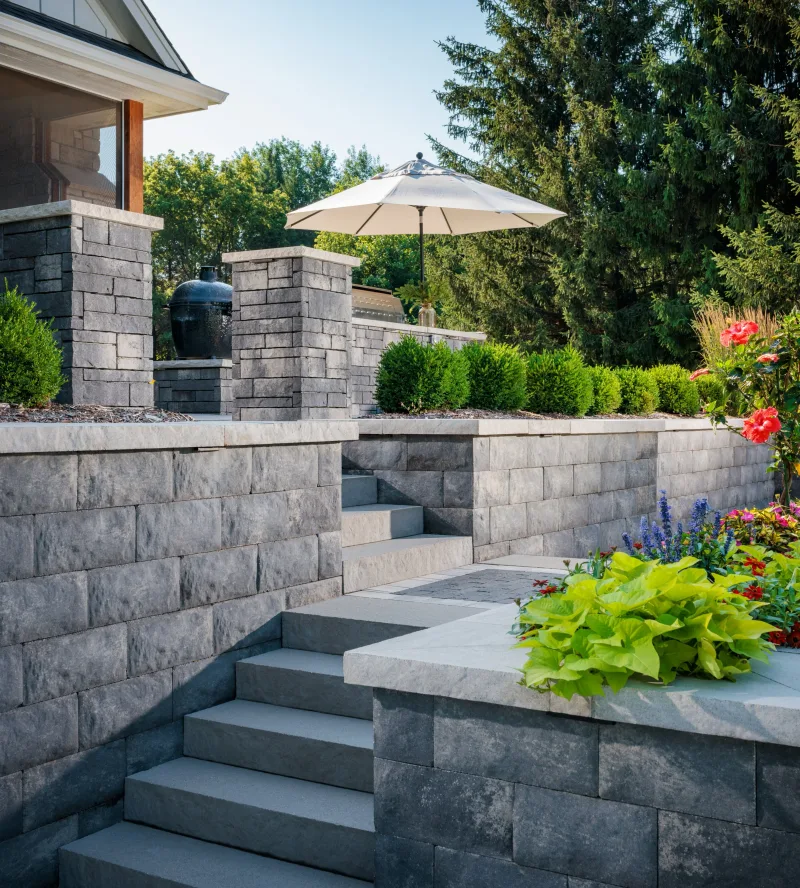 Belgard multi-level terraced hardscape with Diamond Pro Quarry Face retaining walls, Ashlar Tandem columns, Landing Step treads, and Dimensions 6 patio — manufacturer inspiration.