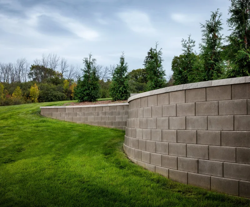 Belgard Diamond Pro Smooth Face Hickory curved retaining and seat wall through manicured lawn — manufacturer inspiration.