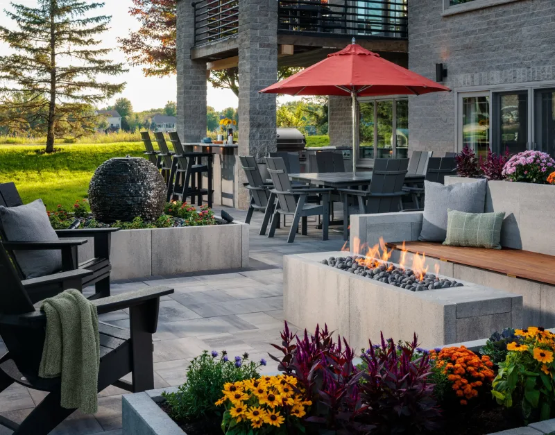 Belgard Dimensions 18 full outdoor room with Dimensions Accent 6x9 border, Artforms seat wall, linear fire, water feature, and dining area — manufacturer inspiration.