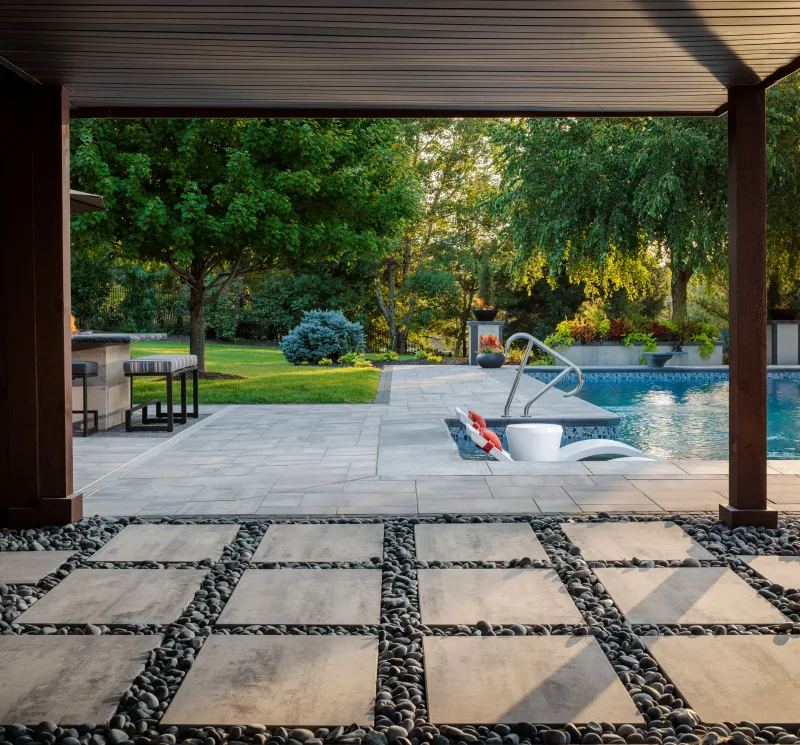 Belgard DimensionsSlab 24x36 stepping pads under pergola with Dimensions 18 pool surround and Artforms outdoor kitchen — manufacturer inspiration.