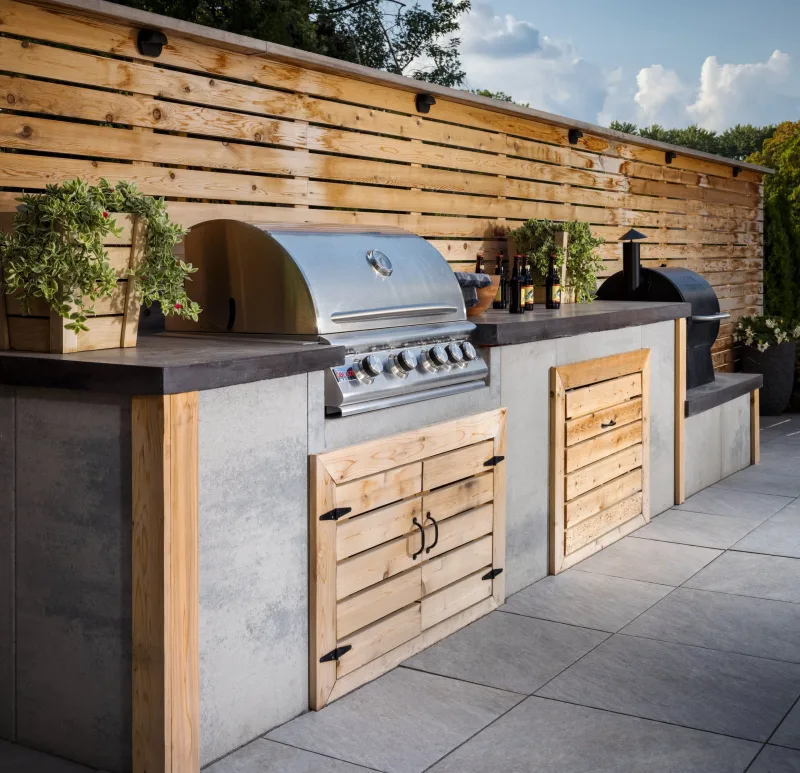 Belgard Artforms outdoor kitchen counter with Quarziti 2.0 Mirage patio floor and cedar privacy fence — manufacturer inspiration.