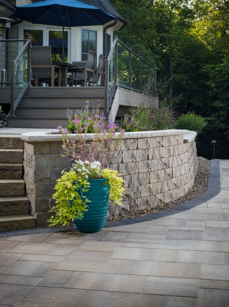 Belgard Melville Slab Tidepool curved seat wall with Brisa Wall Cap coping, Catalina 6x9 paver floor, and composite deck integration — COTY award winner — manufacturer inspiration.